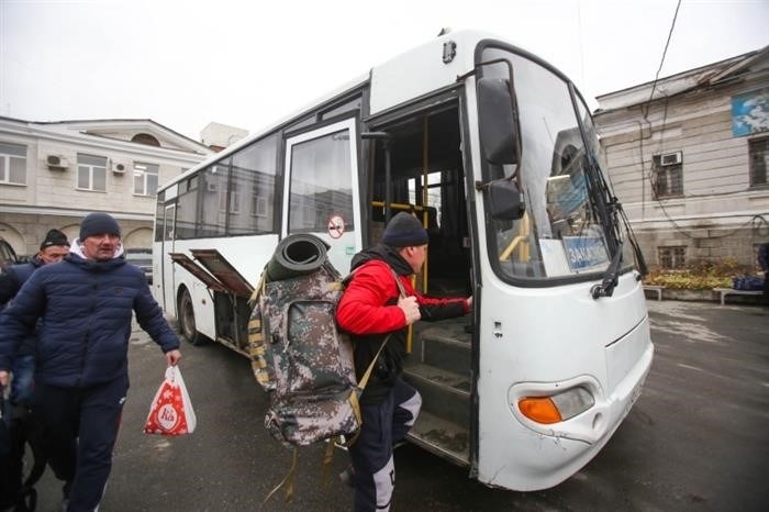 Мобилизованные люди грузятся в автобус.